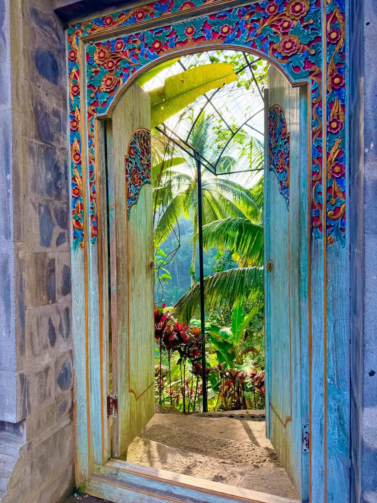 An open carved doorway leading into a garden
